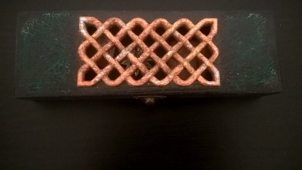 Pentru ca tehnica servetelului nu prezinta o provocare, incercam sa ne reinventam :) Aceasta este o cutie deosebita pentru bijuterii, gandita si mesterita de Andrei: vopsita cu acrilic, alintata cu pasta de crapare, cadorisita cu un model celtic aplicat si, ulterior, traforat, slefuit si sculptat (pentru relief) "la pachet" cu suprafata capacului. La final i s-a aplicat un strat fin de lac transparent care o face mai rezistenta. P.S.: modelul celtic in relief este presarat cu foita de aur, argint si bronz dupa ce, in prealabil, a fost lacuit.